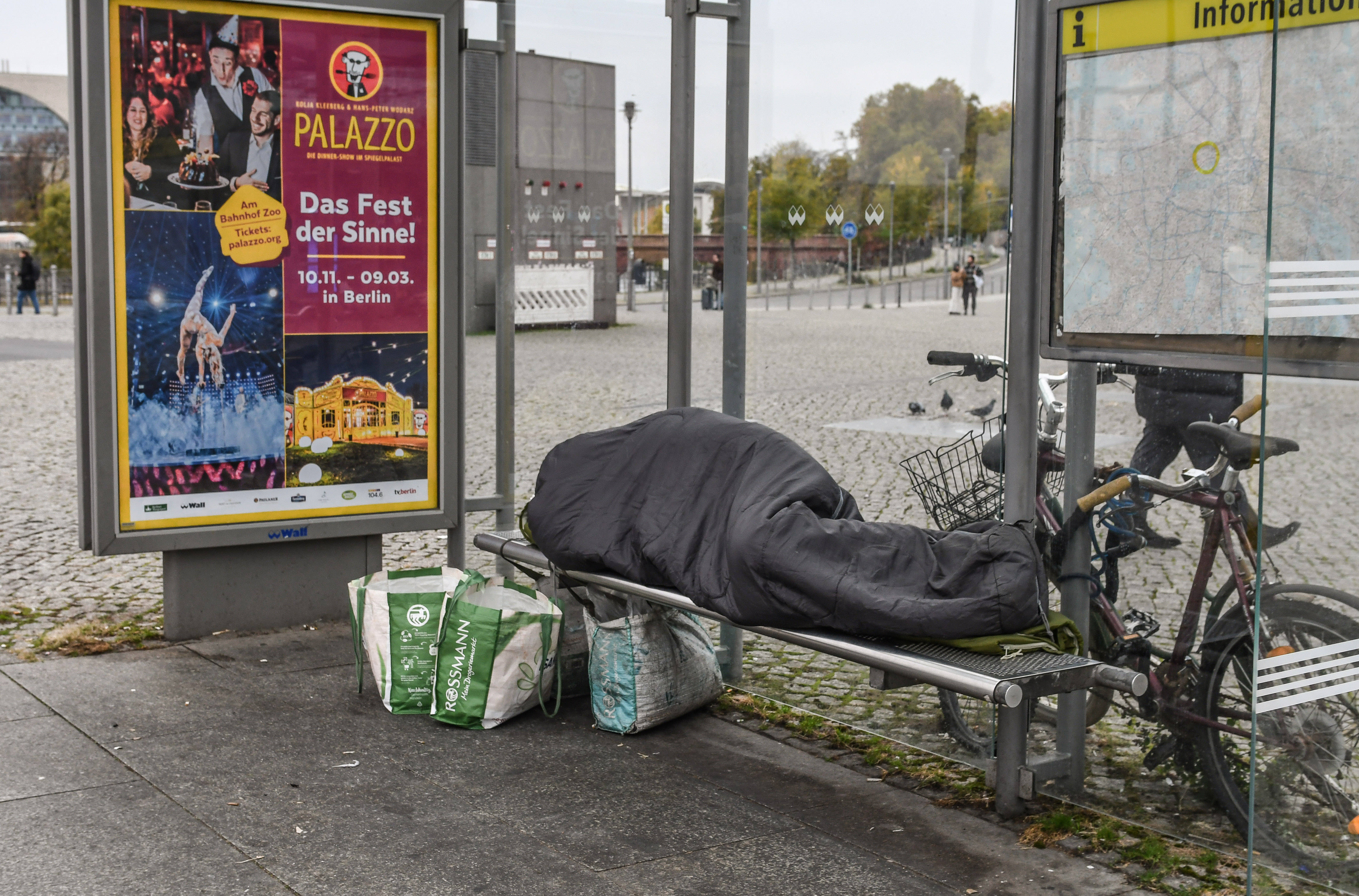 Mann schläft in Schlafsack an Haltestelle