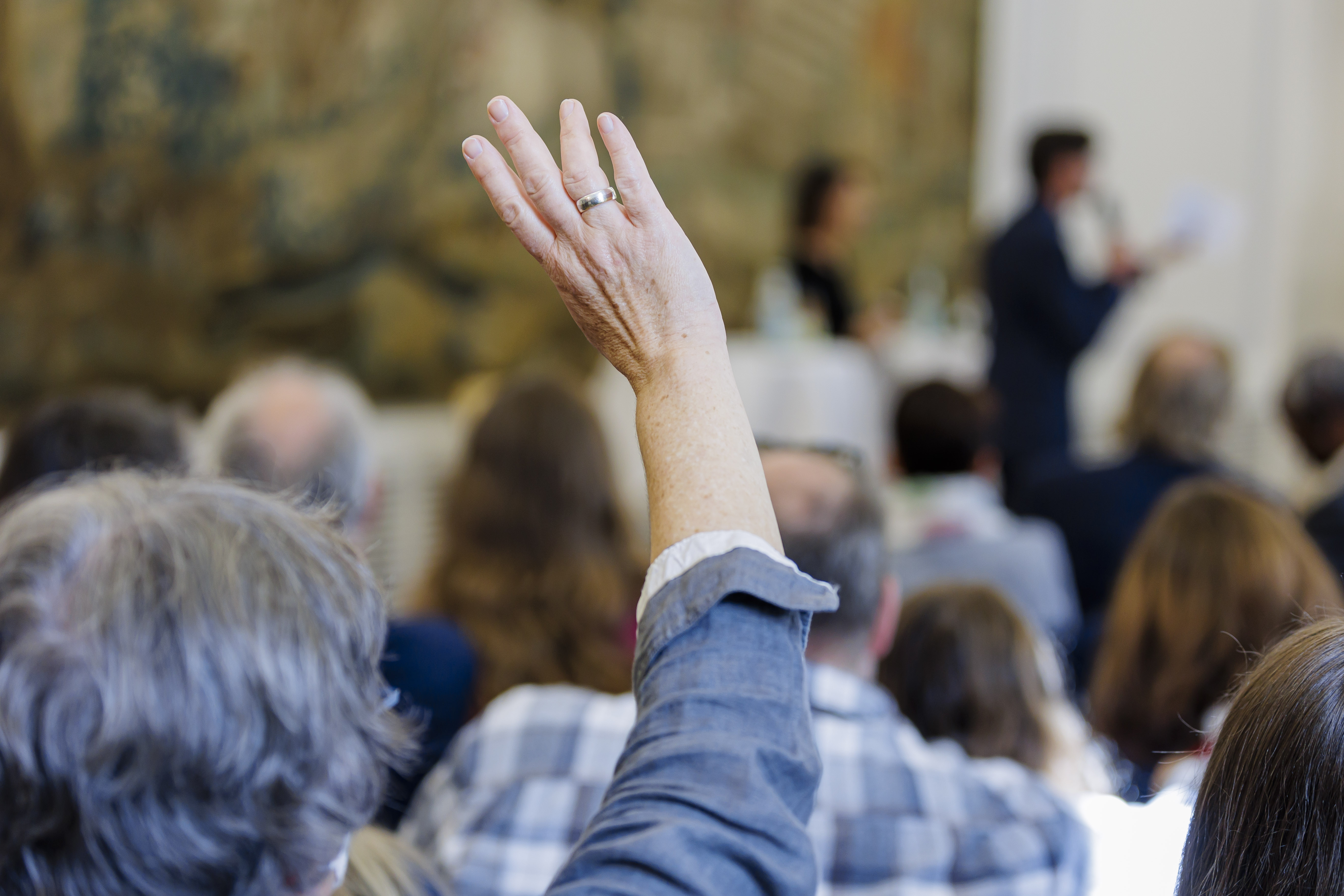 Eine ältere Frau hebt auf einer Versammlung die Hand