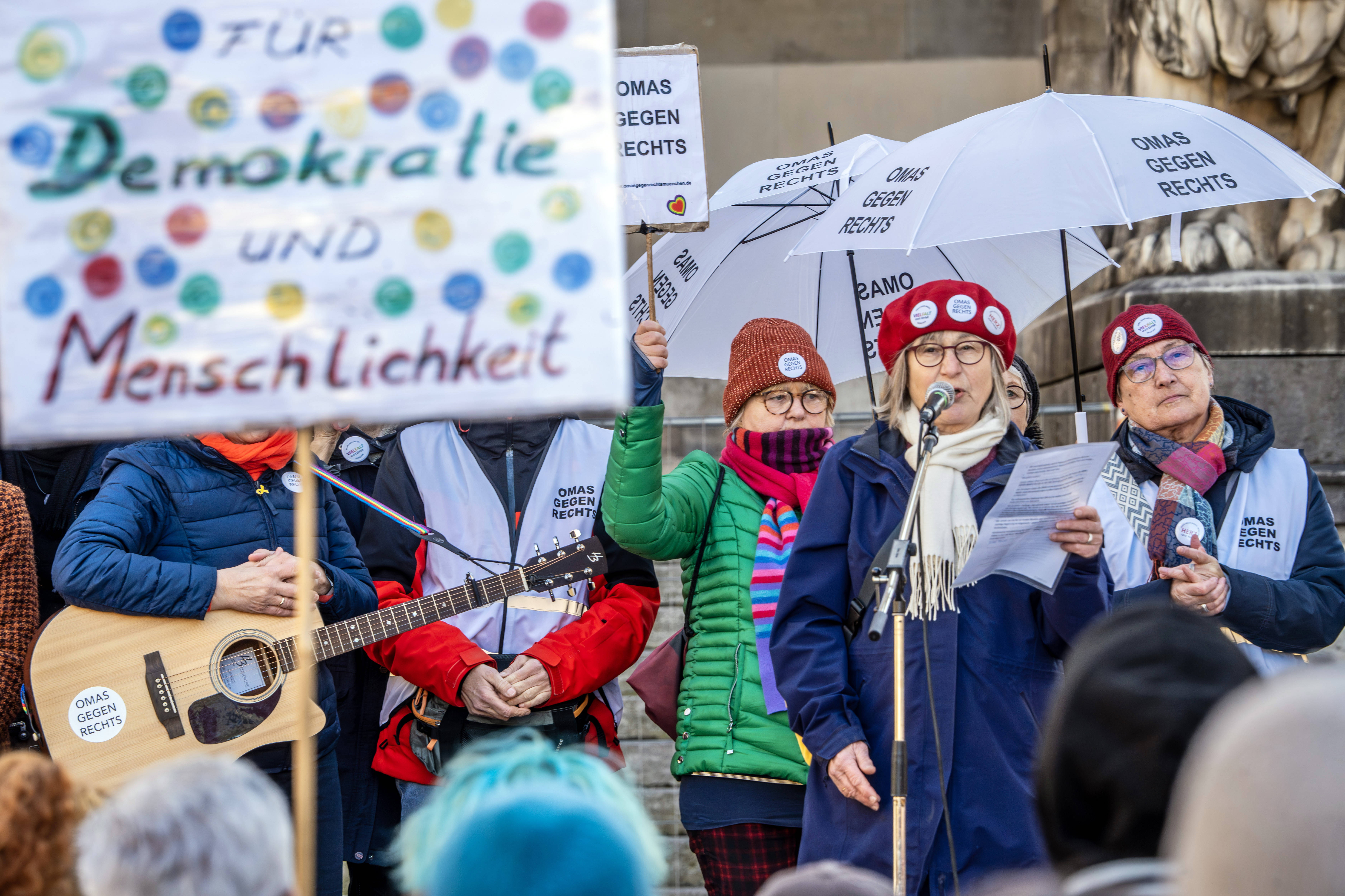 Menschen haten ein Schild mit der Aufschrift „Demokratie und Menschlichkeit“ hoch auf eine Demonstration gegen den Rechtsruck in München. 