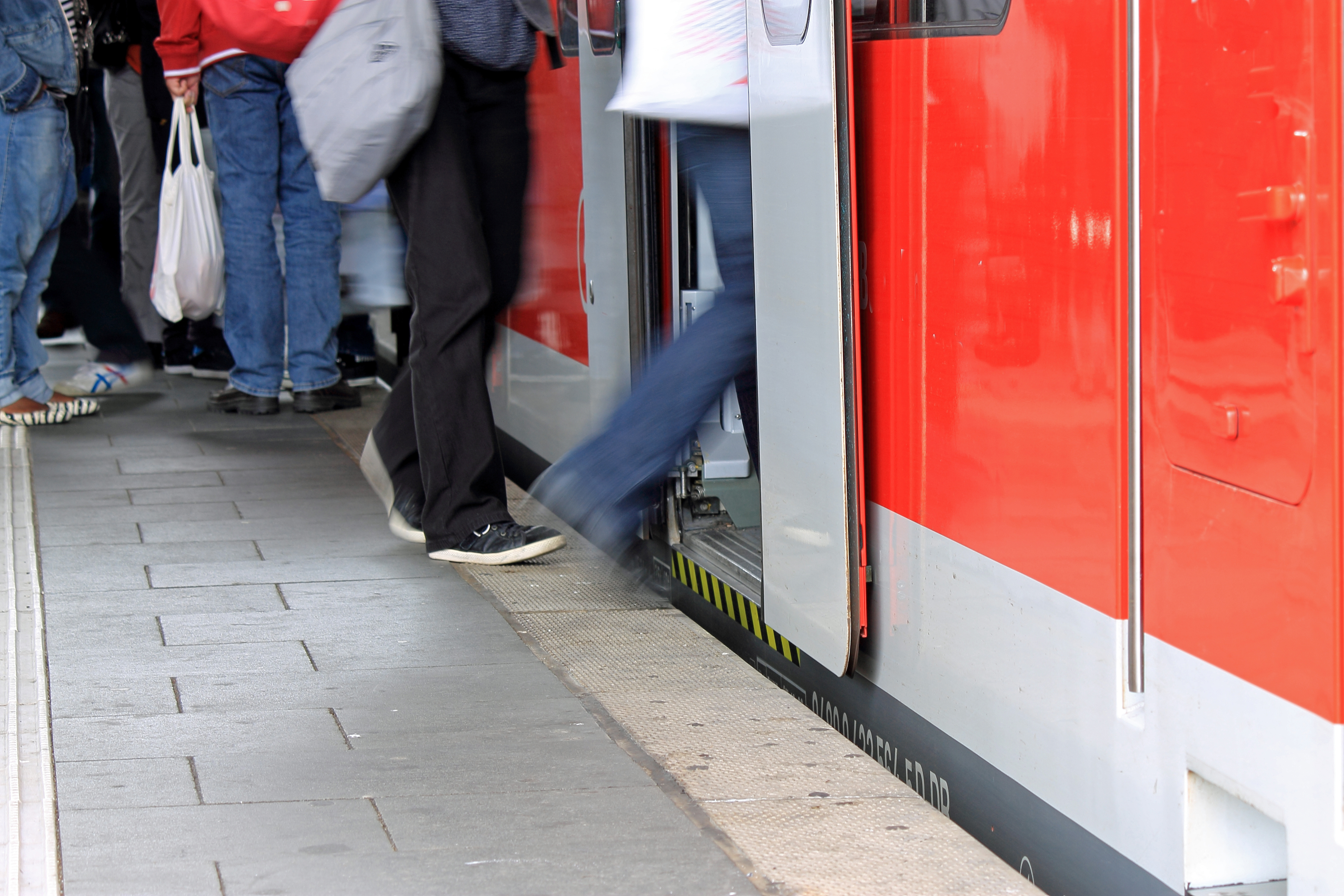 Menschen steigen am Bahnsteig in eine Regionalbahn.