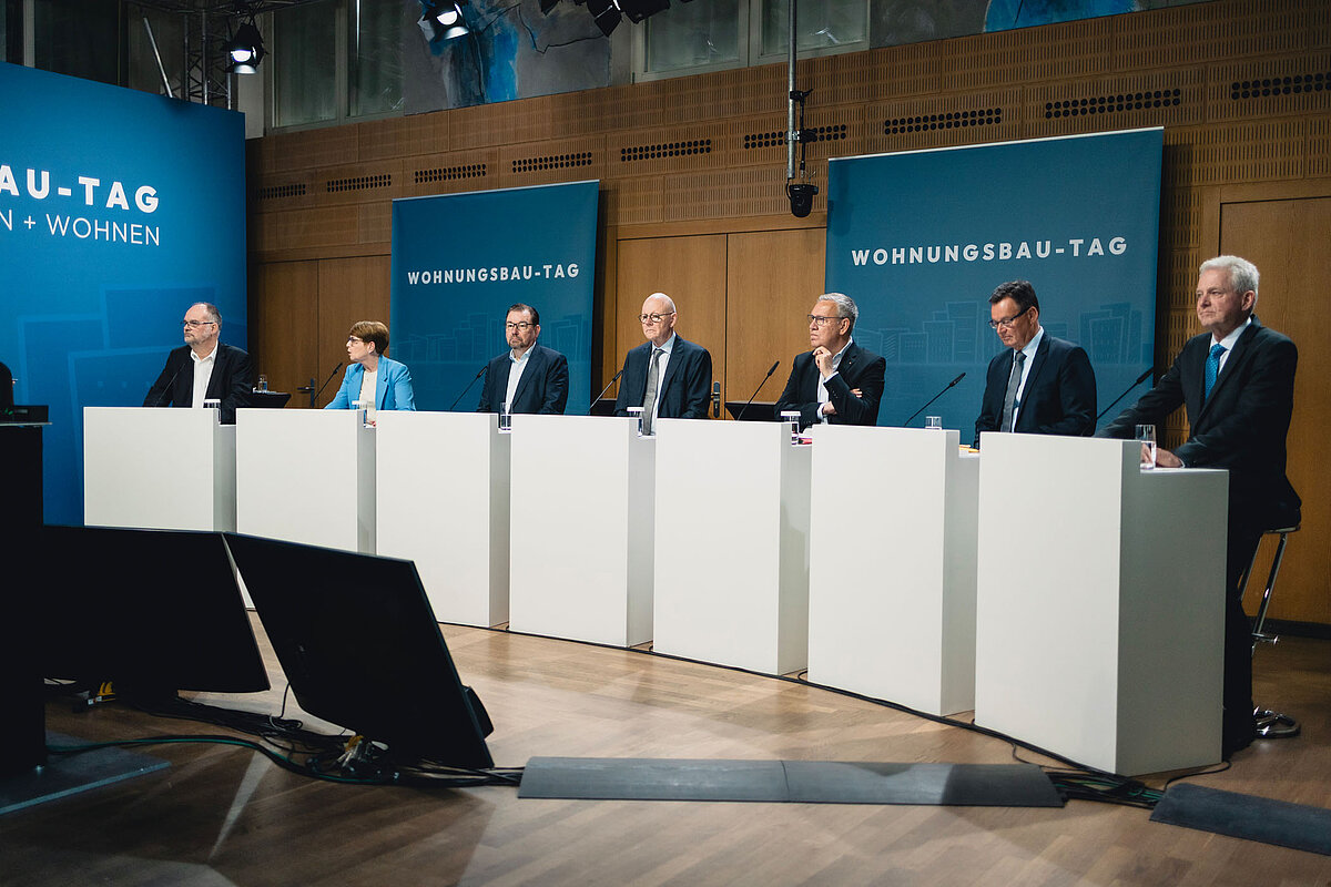 Männer und eine Frau vor Podien