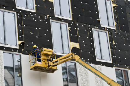 Ein Bauarbeiter bei der Wärmedämmung einer Fassade. 